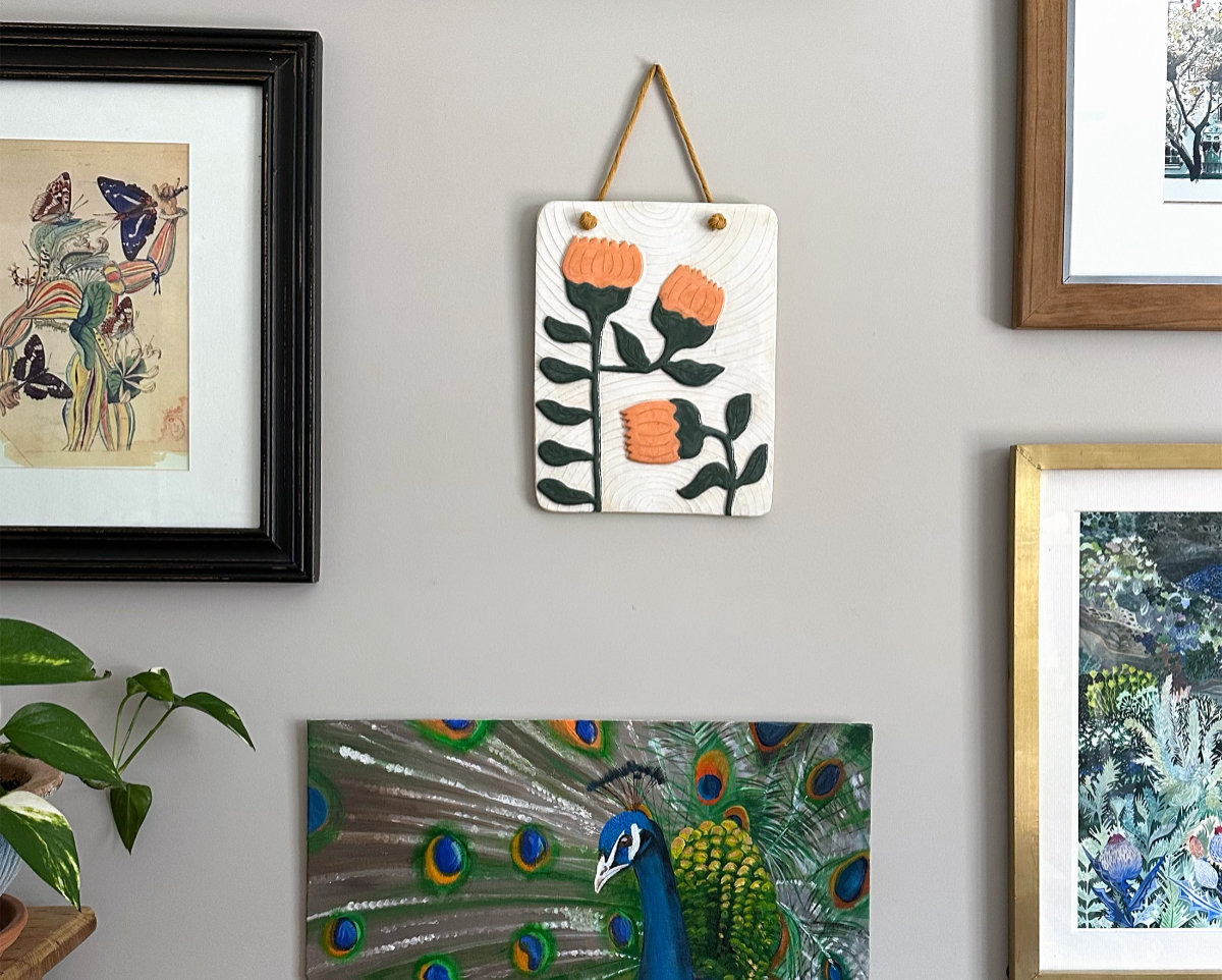 Gallery wall featuring a floral ceramic wall hanging. 